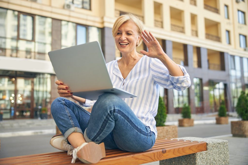 Smiling modern woman greeting someone via Skype